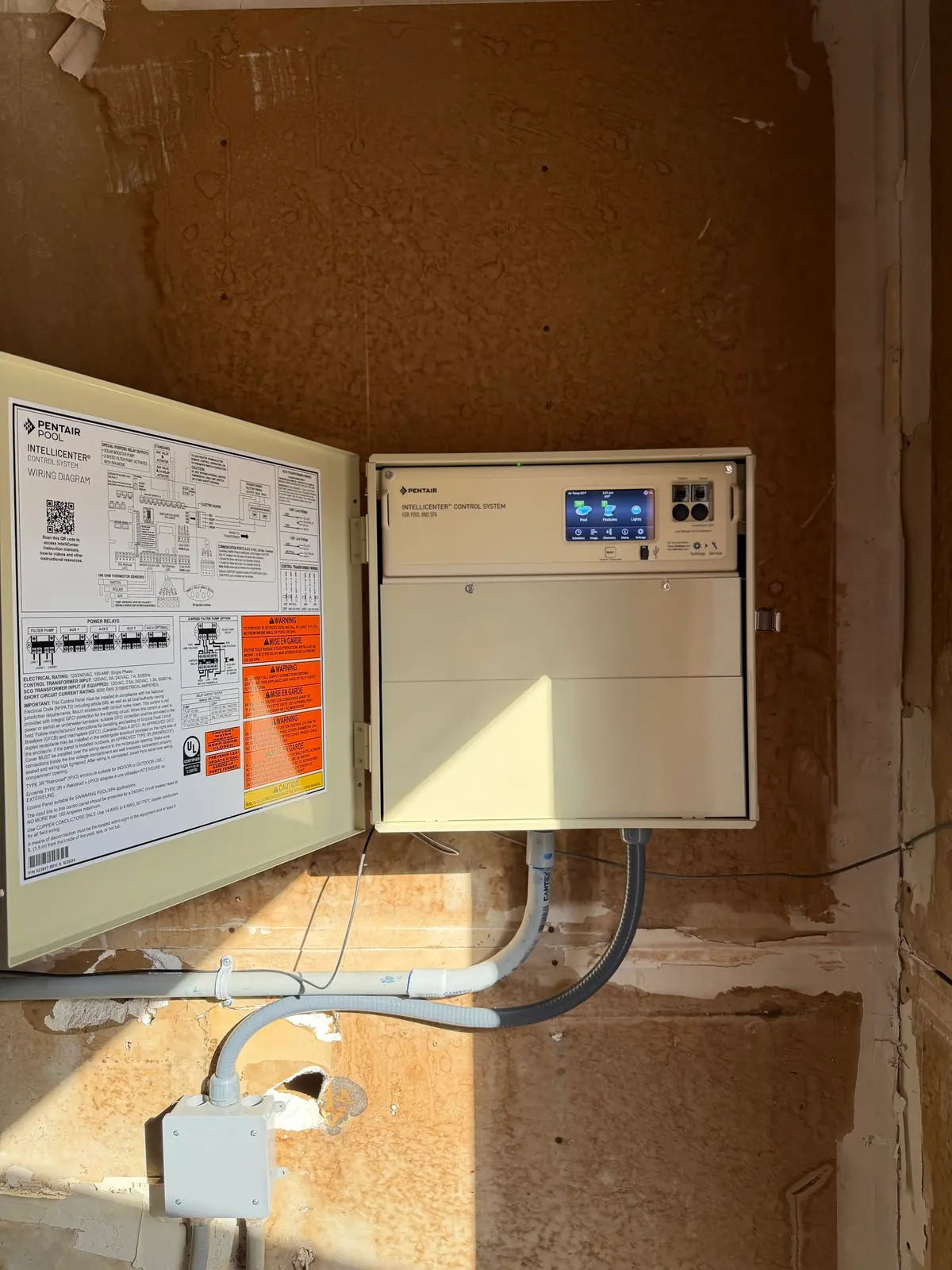 A pool automation control panel mounted on the wall with the door open.